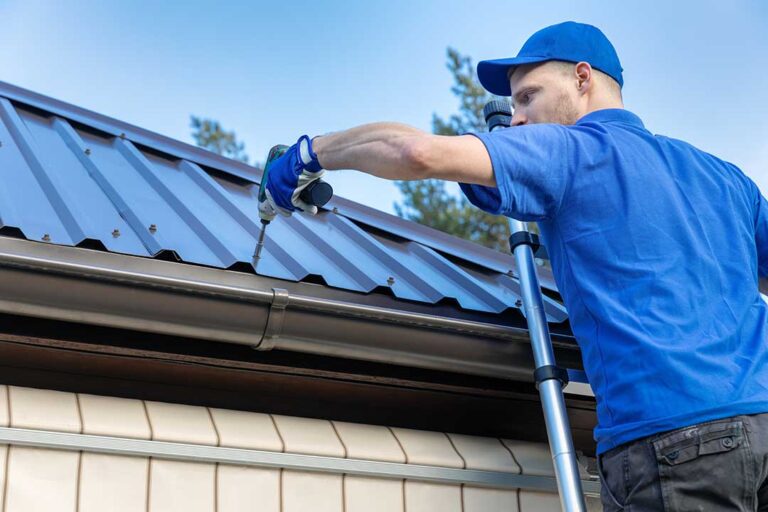 A person wearing safety gear visually inspecting roof shingles for irregular marks after a storm.