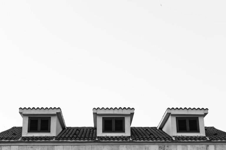 A homeowner examines roof shingles and attic framing for moisture, cracks, and winter weather damage.